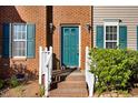 Close-up of the front entrance featuring a teal door, brick steps, and white railings and green shutters at 3308 Forest Mill Cir, Raleigh, NC 27616