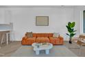 Modern living room with a stylish orange sofa, unique coffee table, and herringbone wood floors at 409 Alston St # 101, Raleigh, NC 27601