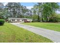 Well-maintained single story home featuring a long driveway, green lawn, and mature trees at 911 Williams Rd, Raleigh, NC 27610