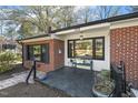 Inviting brick and white trimmed porch featuring dark framed windows and bench at 105 Blanchard St, Fuquay Varina, NC 27526