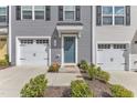 Up close view of a townhome featuring a one-car garage, blue door, and tidy front yard at 1107 Pale Moss Dr, Durham, NC 27704