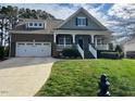 Charming two-story home with a brick facade, a well-maintained lawn, and an inviting front porch at 115 Pecan Harvest Dr, Garner, NC 27529