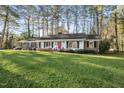 Charming ranch-style home with brick and siding exterior, red front door, and a lush green lawn at 11801 Strickland Rd, Raleigh, NC 27613