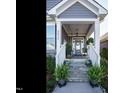 Inviting front porch with stone steps, white columns, a hanging swing, and decorative plants at 2036 Big Falls Dr, Wendell, NC 27591