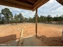 Unfinished backyard showing a view from the covered porch, with a natural landscape of trees in the distance at 228 Dove Rd, Cameron, NC 28326
