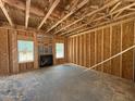 Unfinished living room featuring exposed wood framing, two windows, and a fireplace set against the unfinished walls at 228 Dove Rd, Cameron, NC 28326