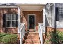 Home entrance features a brick facade, white railings, and a black front door for welcoming curb appeal at 2608 Broad Oaks Pl, Raleigh, NC 27603