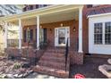 Inviting brick front porch with classic columns, seating area, and decorative front door at 2900 London Bell Dr, Raleigh, NC 27614