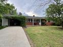 Classic brick home featuring a welcoming front porch, a covered carport, and a well-maintained front lawn at 300 Lakeside Dr, Garner, NC 27529