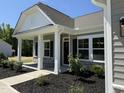 Inviting front porch featuring stone accents, black shutters, landscaped garden, and clearly displayed address at 4013 Kingcraig Ln, Zebulon, NC 27597