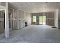 An unfinished open-concept living room boasts a fireplace, ample natural light, and an accessible sliding glass door at 4013 Kingcraig Ln, Zebulon, NC 27597