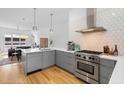 Modern kitchen with gray cabinets, stainless steel appliances, a white backsplash, and light hardwood floors at 402 Chavis Way, Raleigh, NC 27601