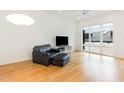 Modern living room featuring hardwood floors, a leather sofa, and large windows at 402 Chavis Way, Raleigh, NC 27601