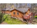 A full rear view of a cozy home with a deck and outdoor stairs in wooded area at 501 Hiddenbrook Dr, Durham, NC 27703