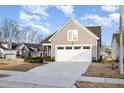 Home featuring a two-car garage, gray siding, and trimmed landscaping, with a neighborhood in the background at 101 Maroon Ct, Raleigh, NC 27610