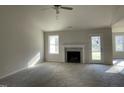 Spacious living room featuring a fireplace, neutral carpet, and ample natural light from two windows at 102 Heatherglenn Cir, Princeton, NC 27569