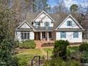 Stately home featuring a well-manicured lawn, mature trees, and covered front porch at 108 Ironwoods Drive Dr, Chapel Hill, NC 27516