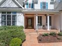 Charming home featuring a decorative wood and glass front door, rocking chairs, and blue shutters at 108 Ironwoods Drive Dr, Chapel Hill, NC 27516