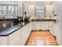 Bright kitchen featuring white cabinets, modern appliances, hardwood floors, and large windows at 12 Montcrest Dr, Durham, NC 27713