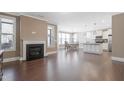 Open concept living area featuring hardwood floors, fireplace, kitchen island, and dining area with ample light at 125 Station Dr, Morrisville, NC 27560