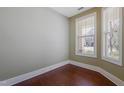 Bright, vacant room featuring two large windows, neutral walls, and pristine dark hardwood flooring at 125 Station Dr, Morrisville, NC 27560