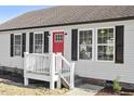 Close-up of a house featuring a red door and a white picket fence on a sunny day at 176 Clear Water Dr, Smithfield, NC 27577