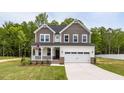 Charming two-story home with a covered porch, two-car garage, and manicured lawn at 303 Old Fashioned Way, Lillington, NC 27546