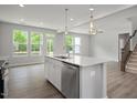Open-concept kitchen features stainless appliances, island with breakfast bar, and seamless flow to the living spaces at 303 Old Fashioned Way, Lillington, NC 27546