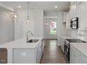Modern kitchen with white cabinets, stainless steel appliances, island with sink, and view to the front of the home at 303 Old Fashioned Way, Lillington, NC 27546