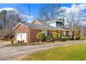 Brick home featuring an attached garage and well-maintained landscaping with mature trees at 712 Springwood Ave, Gibsonville, NC 27249