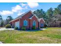 Side view of a brick home featuring an attached garage, blue shutters, and landscaped yard at 7687 Mattie Rd, Rocky Mount, NC 27803