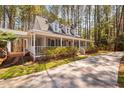 Low-angle view of a Cape Cod home with a wrap-around porch, showcasing its inviting curb appeal at 7917 Blaney Franks Rd, Apex, NC 27539