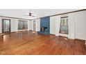 Spacious living room featuring hardwood floors, a blue brick fireplace, and large windows with natural light at 7917 Blaney Franks Rd, Apex, NC 27539