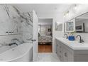 The bathroom has marble walls with a sleek bathtub and double vanity sinks overlooking the bedroom at 8504 Old Nc 86, Chapel Hill, NC 27516