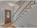 Bright foyer with hardwood floors, staircase with white railings, and a decorative front door at 8704 Paddle Wheel Dr, Raleigh, NC 27615