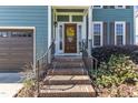 Inviting brick front porch with a wooden door, yellow wreath, and manicured landscaping at 8704 Paddle Wheel Dr, Raleigh, NC 27615