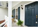 Inviting front porch featuring a comfortable seating area with elegant blue door and wall-mounted lighting at 9724 Dansington Ct, Raleigh, NC 27615