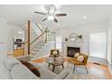 Bright living room with a fireplace, hardwood floors, ceiling fan, and staircase to the second floor at 9724 Dansington Ct, Raleigh, NC 27615