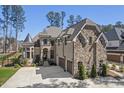 Beautiful stone and brick home featuring manicured landscaping, three car garage, and an elegant turret at 119 November Dr, Durham, NC 27712