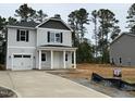 Two-story home with gray siding, black shutters, attached garage, and a long driveway in a wooded neighborhood at 187 Regis Ln # 10, Coats, NC 27521