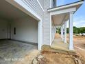 Open garage showcasing its concrete flooring and light gray siding complemented by white columns and trim at 187 Regis Ln # 10, Coats, NC 27521