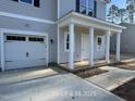 Close up of the charming house featuring a one-car garage and a welcoming porch with white columns at 187 Regis Ln # 10, Coats, NC 27521
