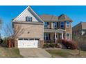 Inviting exterior showcasing a brick facade, two-car garage, manicured lawn, and covered front porch at 1950 Firenza Dr, Apex, NC 27502