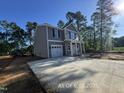 View of the new home featuring a long driveway, two-story construction, and a well-lit exterior, surrounded by trees at 205 Regis Ln # 11, Coats, NC 27521