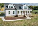 Beautiful new two-story farmhouse with white siding, black roof, welcoming porch, and well-manicured front yard at 2142 Henderson Tanyard Rd, Pittsboro, NC 27312