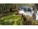 View of a lush backyard, a wooden deck and solar panels on the roof of a house in a wooded setting at 2820 Mattlyn Ct, Raleigh, NC 27613
