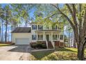 Inviting two-story home with a classic front porch, complemented by lush greenery and a spacious driveway at 3 Guilder Cv, Durham, NC 27713