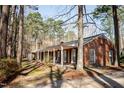 Single story brick home featuring a long covered porch surrounded by mature trees at 4105 Lassiter Rd, Wake Forest, NC 27587