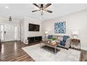 Living room with hardwood floors, neutral walls, a ceiling fan, television, and front door at 50 Yelverton Ct, Holly Springs, NC 27540