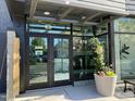 Stylish building entrance with glass doors, address number, and decorative greenery at 610 Trent Dr # 202, Durham, NC 27705